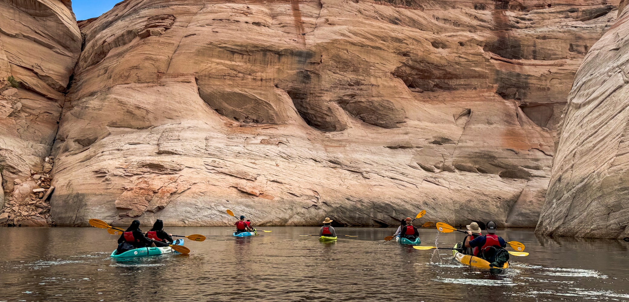 group of kayakers paddling through a canyon on lake powell led by a trained guide