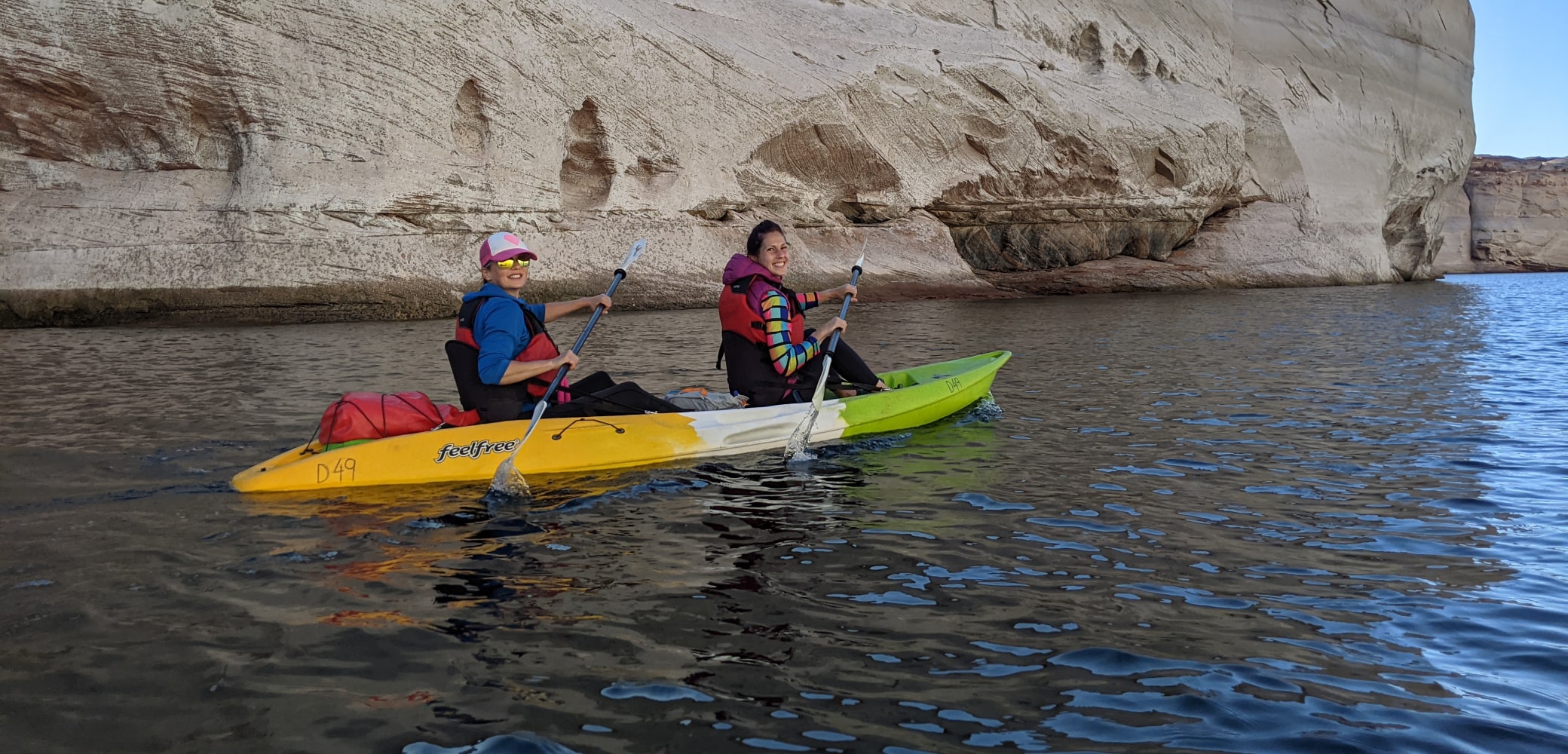 two women in a double kayak paddling on lake powell