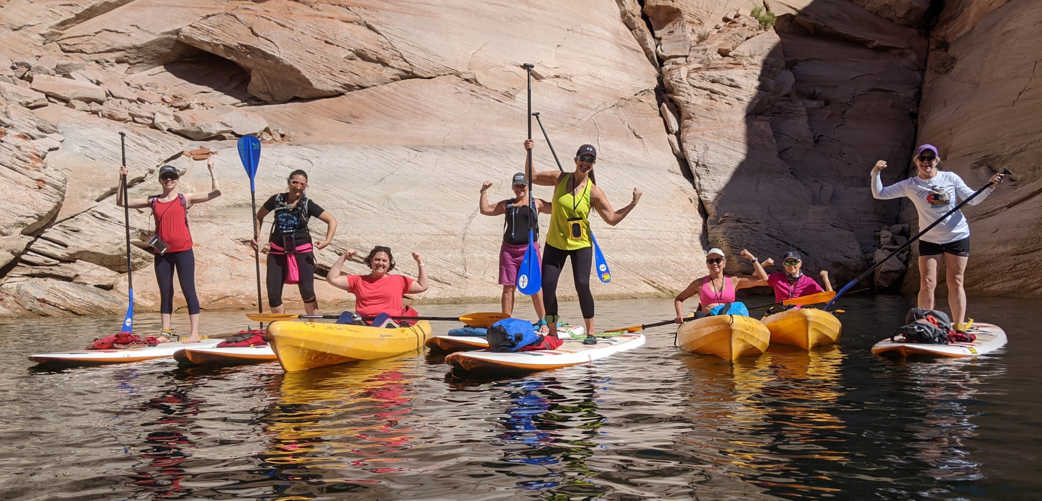 group of women on stand up paddleboards and in kayaks on a private tour of lake powell