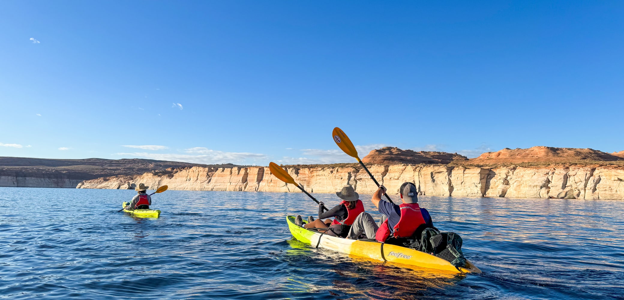 two people in a double kayak being led by a guide on a private kayak tour on lake powell