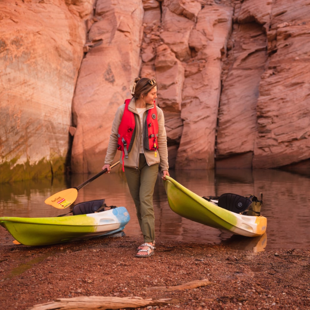 woman pulling her kayak up on the shore of a slot canyon off of lake powell