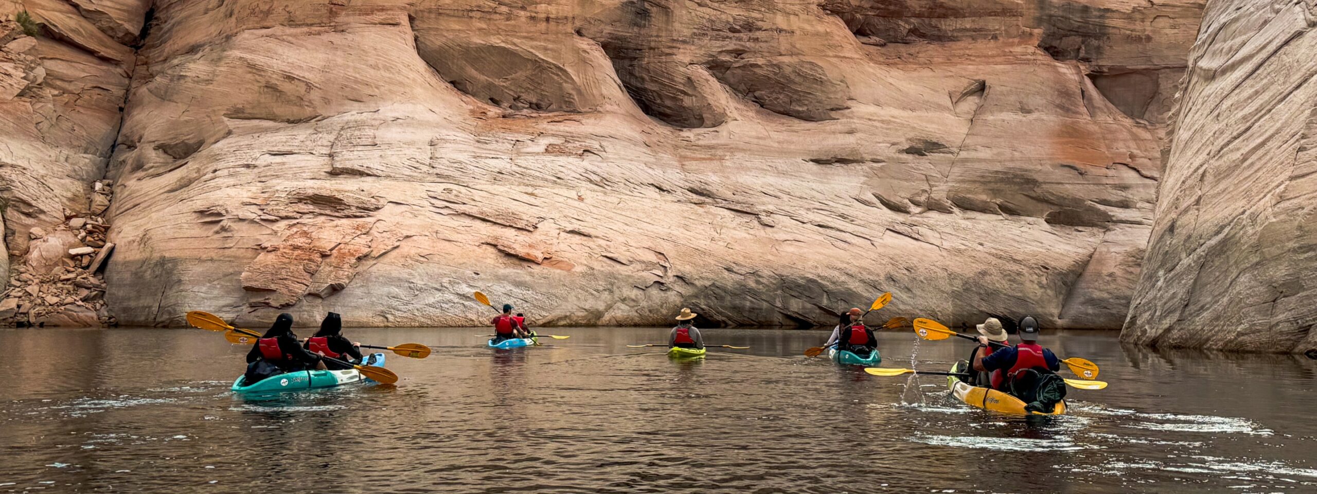 group of kayakers safely paddling through a canyon of lake powell after receiving a thorough safety briefing