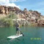 a man on a paddleboard with red rock in the background