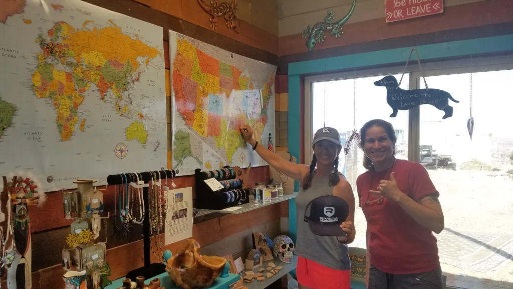 two women pose in front of a map on a wall