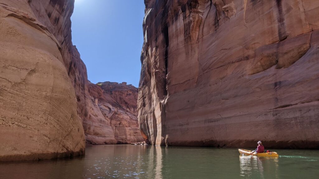 a woman paddles through lake powell's rock canyons