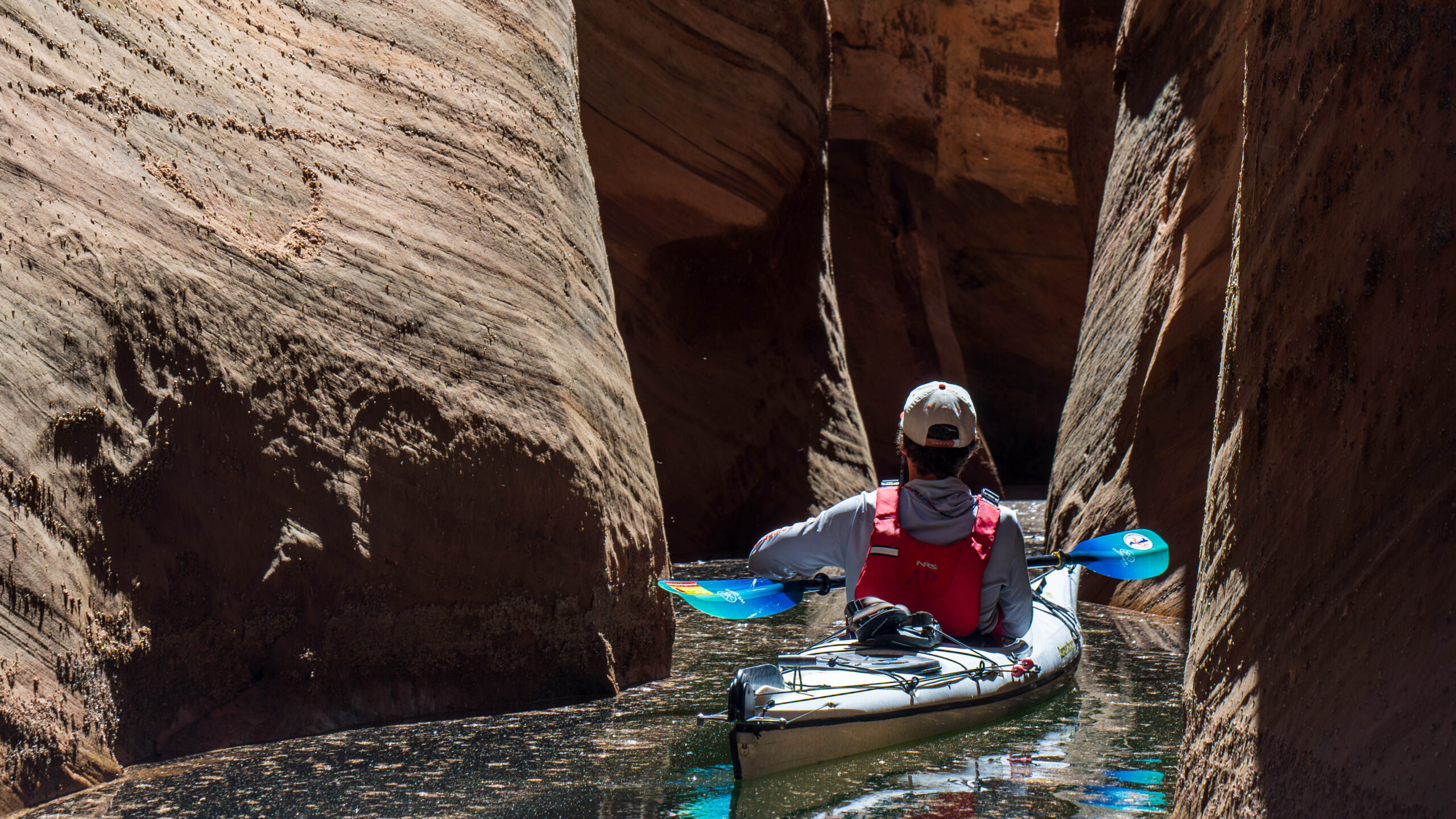 A person navigates a narrow canyon on a kayak